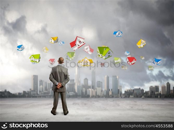 Back view of confident businessman looking at city with items flying in air