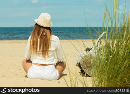 Back view of long haired woman on beach.. Summer time. Rear view of gorgeous girl with long hair on beach seaside. Attractive and fashion woman tourist resting outdoor.