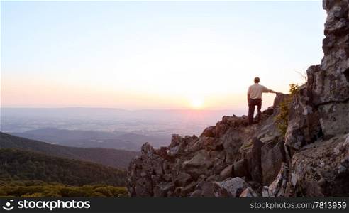 Back view of man watching sunset from rocky summit of Stony Man on Skyline Drive in Virginia