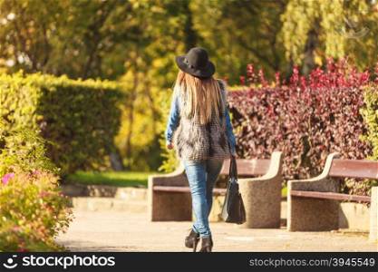 Back view of stylish woman on air. Female fashion. Back view of attractive long haired model wearing stylish clothes in park. Fashionable young model spending time on air.