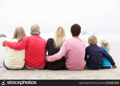 Back View Of Three Generation Family Sitting On Winter Beach Together