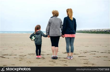 Back view of three generations female watching the sea in autumn. Three generations female watching the sea