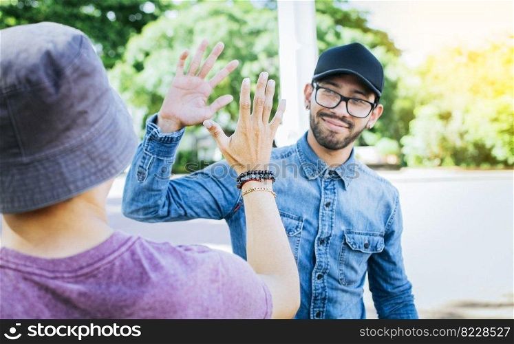 Back view of two smiling friends shaking hands on the street. Two smiling friends shaking hands in a park. Concept of two friends greeting each other with a handshake on the street