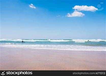 back view of unidentified man with surf board in blue ocean water. Summer beach panoramic view