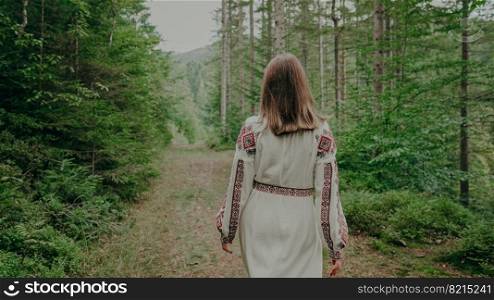 Back view of unrecognizable ukrainian woman walking in fir forest, Carpathian mountains nature. Girl in traditional embroidery vyshyvanka dress. Ukraine, freedom, ethnic national costume.. Back view of unrecognizable ukrainian woman walking in fir forest, Carpathian mountains nature. Girl in traditional embroidery vyshyvanka dress. Ukraine, freedom, ethnic national costume