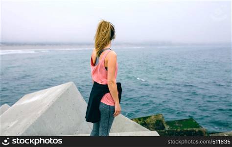 Back view of unrecognizable young woman watching the sea. Unrecognizable young woman watching the sea