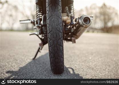 Back view of wheel and exhaust pipe of motorcycle on the road. Wheel and exhaust pipe of motorcycle on road