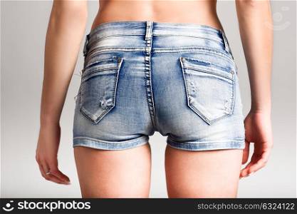 Back view of woman wearing denim shorts on white background