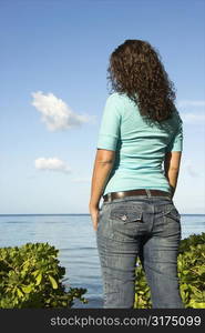 Back view of young adult Caucasian brunette female looking out over body of water.