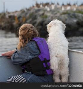 Back view of young girl with her dog in a boat at Lake of the Woods, Ontario