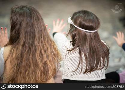Back view of young girls giving points with their fingers.