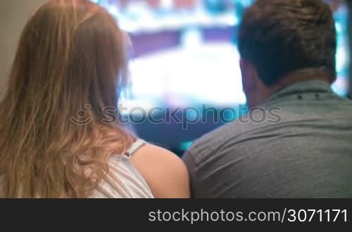 Back view of young man and woman staring at TV screen. Entertainment time or television addicts