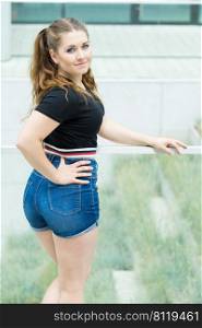 Back view of young teenage woman wearing short blue jeans denim shorts enjoying summer weather. Behind view of teenager girl