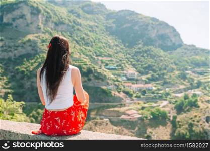 Back view of young woman in straw hat with italian village on the background of Amalfi Coast, Italy. Summer holiday in Italy. Young woman in Positano village on the background, Amalfi Coast, Italy