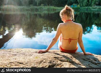 Back view portrait of a beautiful relaxed woman on the beach with blue water background