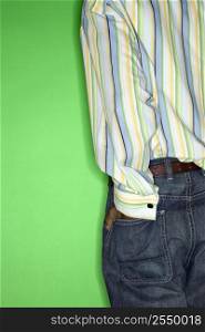 Back view torso of African-American teen boy with hand in back pocket of jeans standing against green background.