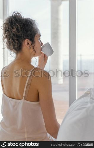 back view woman pijama drinking coffee