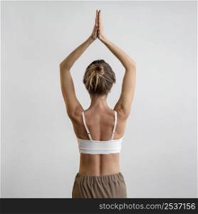 back view woman practicing yoga home