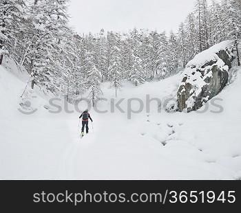 Backcountry skier walks in a snowy mountain valley. Gressoney, Val d&acute;Aosta, Italy, Europe.