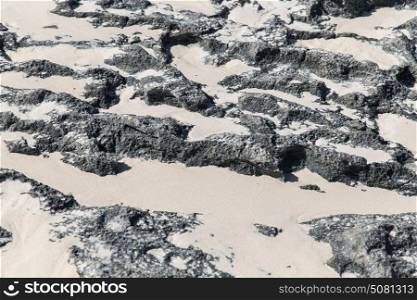 background and texture concept - close up of stone or volcanic rock surface with sand. close up of stone or volcanic rock with sand