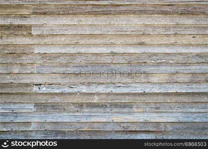 background and texture of an old, weathered wood siding of abandoned farm house