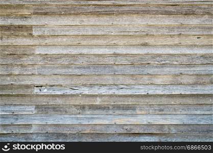 background and texture of an old, weathered wood siding of abandoned farm house