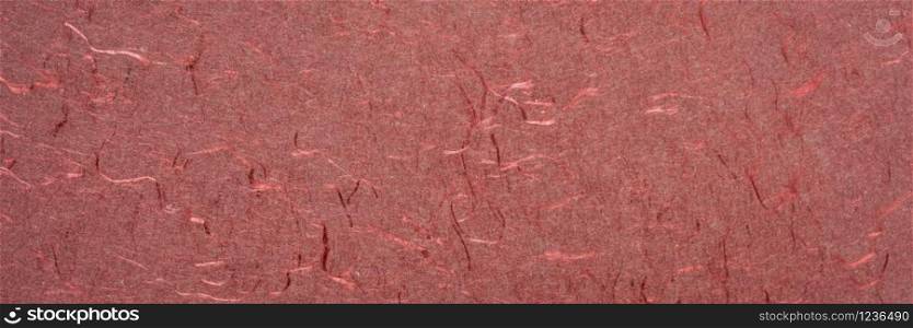 background and texture of red handmade Indian paper created from recycled cotton fabric with silk fibers, panorama banner