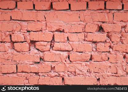 Background and texture painted red brick wall of broken and uneven bricks with uneven cement seam.