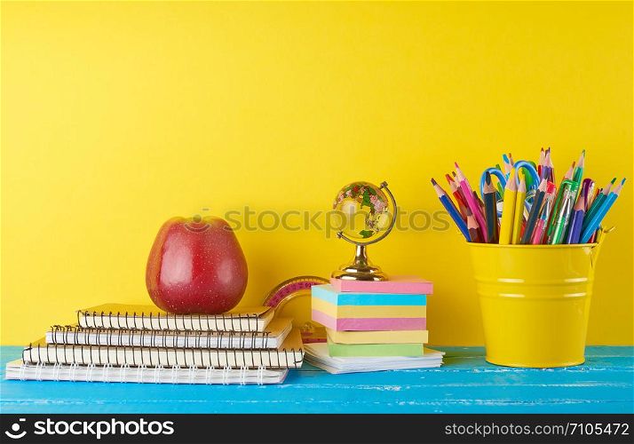 background back to school with children&rsquo;s stationery pencils, notepad, apple, glass globe on a yellow background