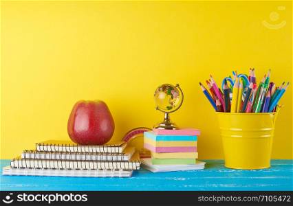 background back to school with children&rsquo;s stationery pencils, notepad, apple, glass globe on a yellow background