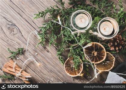Background for christmas with burning candles and natural decoration on rustic wooden board. Background with pine branches and space for your text.