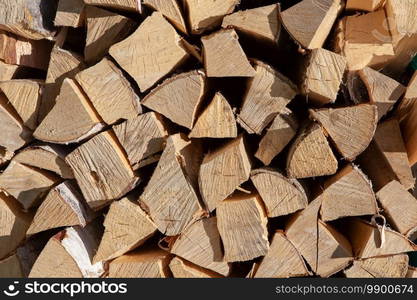 Background from stack of firewood from birch tree, for heating house, stacked in backyard, uncut wood, birch. Concept eco-friendly home heating during cold season. Overall plan. Horizontal format.