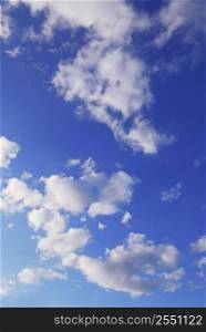 Background if bright blue sky with white fluffy clouds