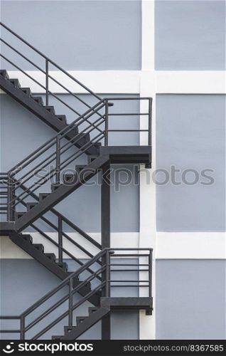 Background of black steel fire escape on gray and white building wall in under construction