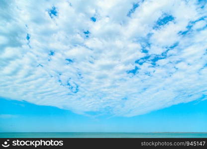 background of blue sky with beautiful clouds and a small part of the azure sea in the frame. the focus is selective.