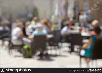 Background of blurred cafe on street of city. Tables and chairs outside in natural bokeh