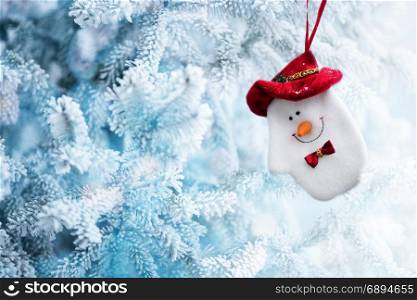 Background of Christmas Snowman Sock Hanging on a Tree Branch in the Frozen Winter Forest, Copy Space