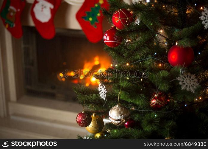 Background of Christmas tree at living room with burning fireplace decorated with traditional stockings for gifts
