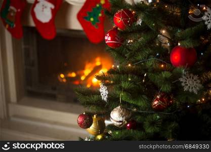 Background of Christmas tree at living room with burning fireplace decorated with traditional stockings for gifts