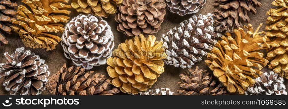 background of decorative pine cones - natural, gold and frosty white painted, winter holidays banner