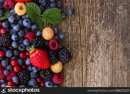 background of fresh colorful berries mix on wooden bakground, top view