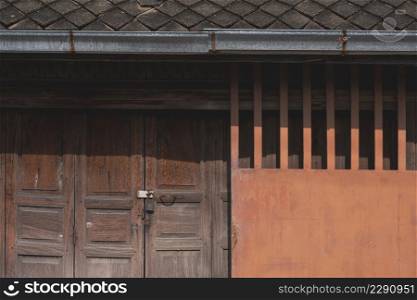 Background of grunge wooden folding door with metal sliding entrance door and clay tile roof of the old rustic house