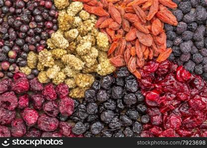 background of healthy dried superfruit berries - blueberry, mulberry, cherry, goji, elderberry, chokeberry, and cranberry