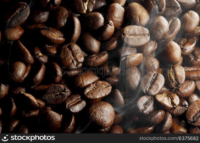 Background of hot roasted coffee beans and steam. Hot roasted coffee beans