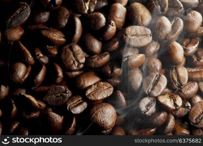 Background of hot roasted coffee beans and steam. Hot roasted coffee beans