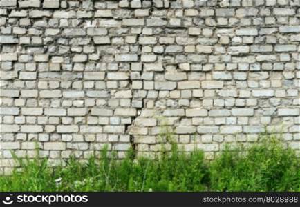 Background of old cracked white brick wall with green grass