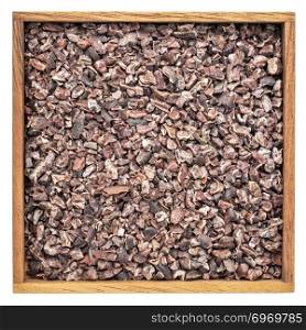 background of raw cacao nibs in an isolated wooden box