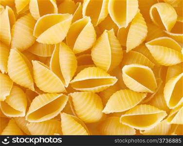 Background of raw pasta shells scattered on the table