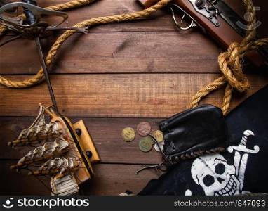 Background of several pirate items lying on a dark wooden surface forming a frame. sword flag pistol