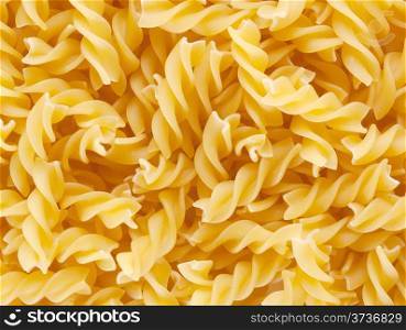 Background of twisted raw pasta scattered on the table